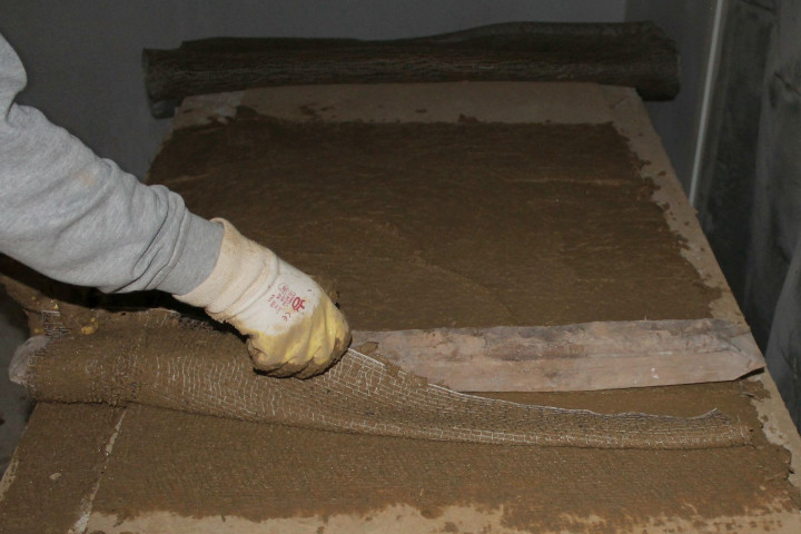 Das bestrichene Gewebe wird um eine der ursprünglich in der Decke verbauten hölzernen Staken gewickelt