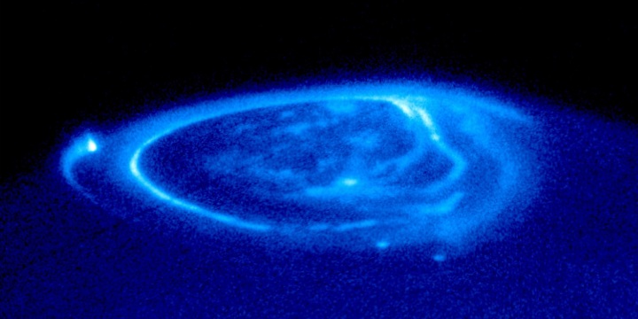 Zu sehen ist ein blaues kreisförmiges Licht über einem Planeten im Weltall.   &copy;Von NASA, ESA & John T. Clarke (Univ. of Michigan)